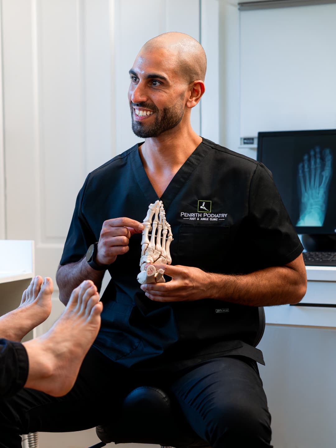 Penrith Podiatry clinician using a skeletal foot model to explain foot anatomy to a patient