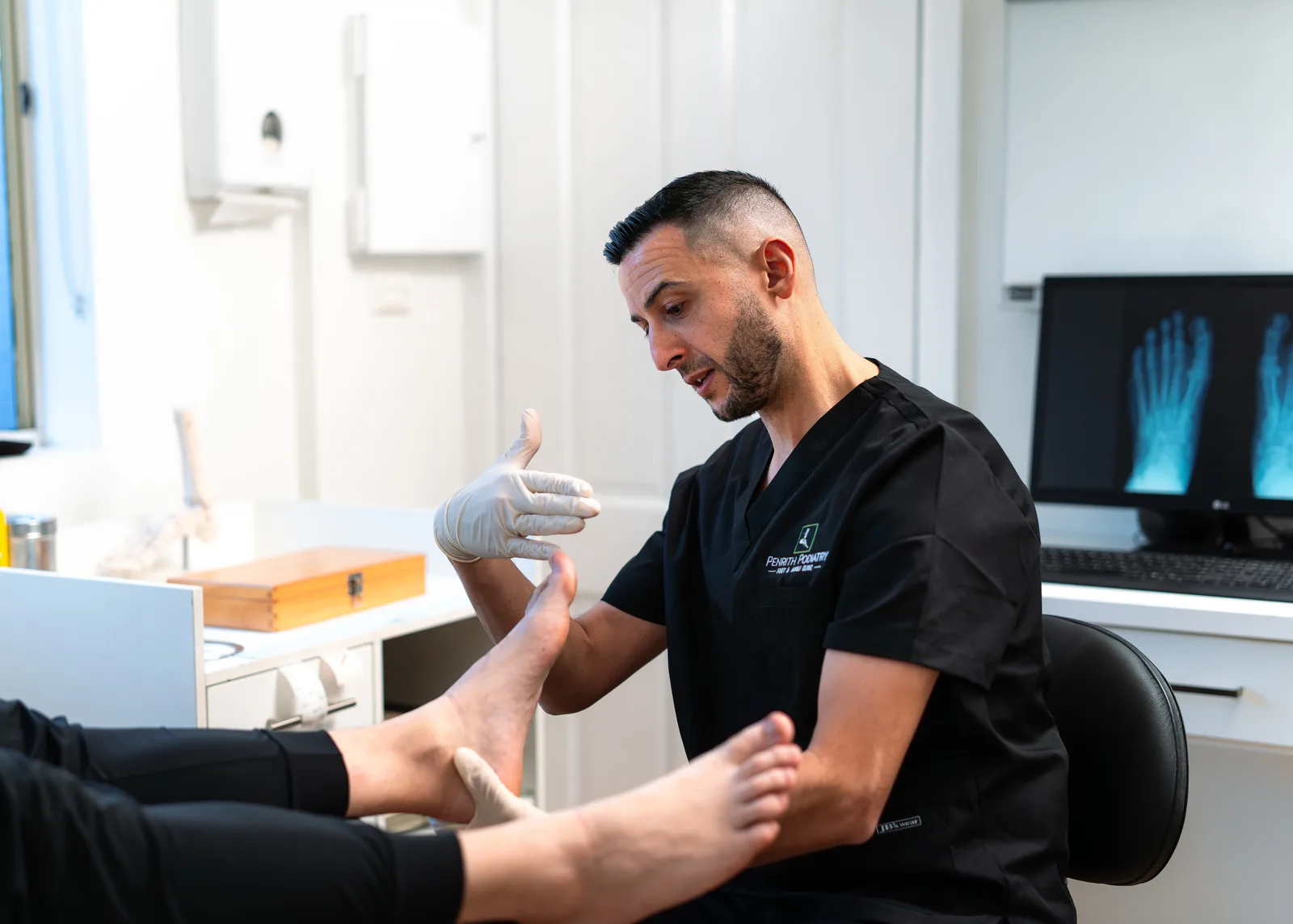 Penrith Podiatry podiatrist assessing a patient's foot with X-ray imaging on screen in the clinic